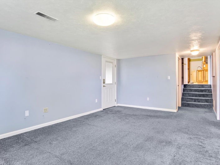 Carpeted empty room featuring stairs, baseboards, and a textured ceiling