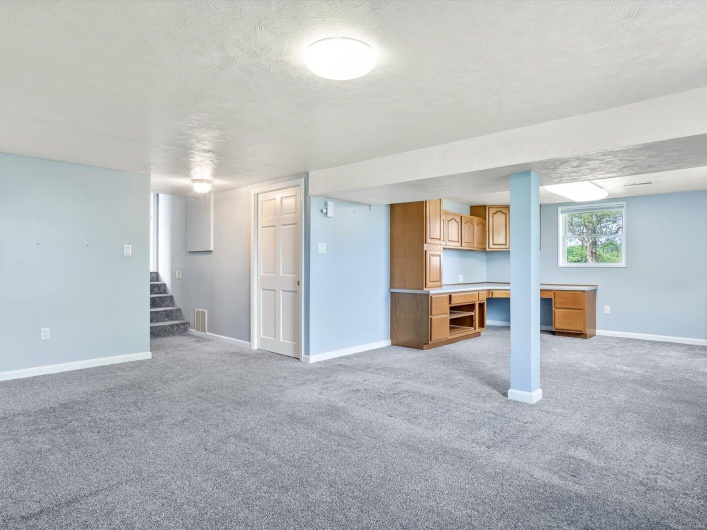 Below grade area featuring light carpet, baseboards, stairway, and a textured ceiling