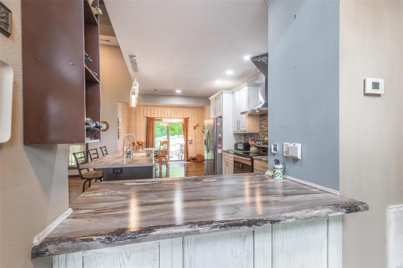 Kitchen with appliances with stainless steel finishes, white cabinets, a textured wall, decorative backsplash, and a peninsula