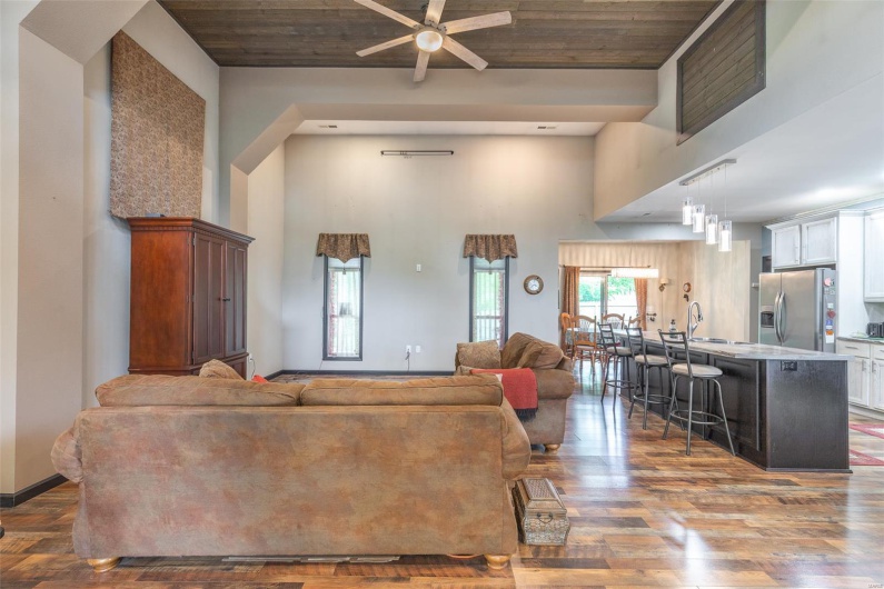 Living area featuring a towering ceiling, wood finished floors, a ceiling fan, and wood ceiling
