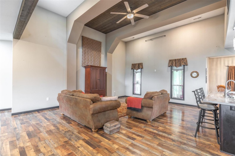 Living area featuring a high ceiling, wood finished floors, a ceiling fan, and baseboards
