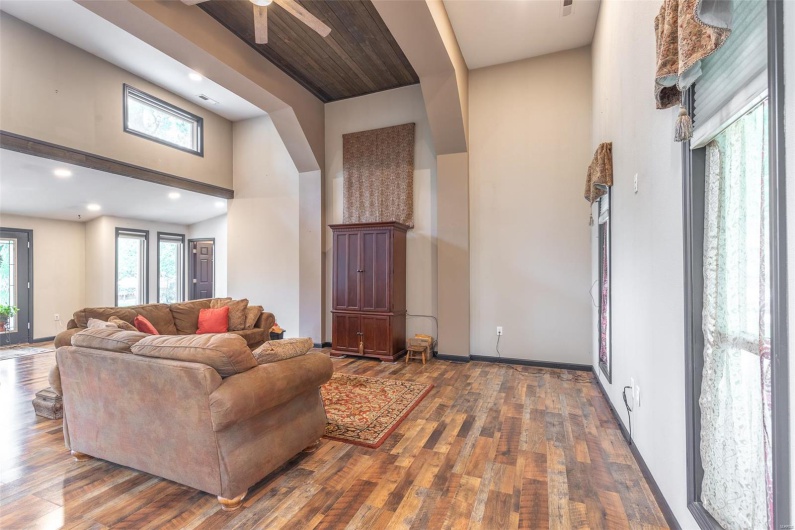 Living room featuring wood finished floors, recessed lighting, a ceiling fan, baseboards, and a towering ceiling