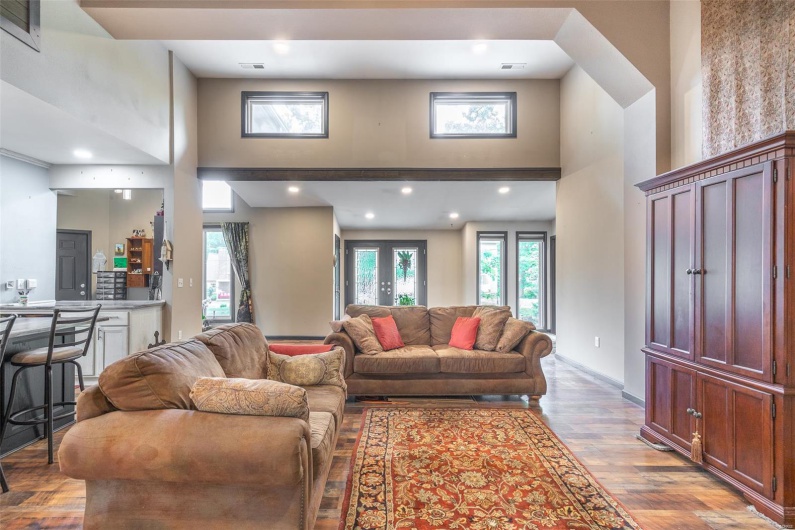 Living area with a high ceiling, wood finished floors, recessed lighting, and baseboards