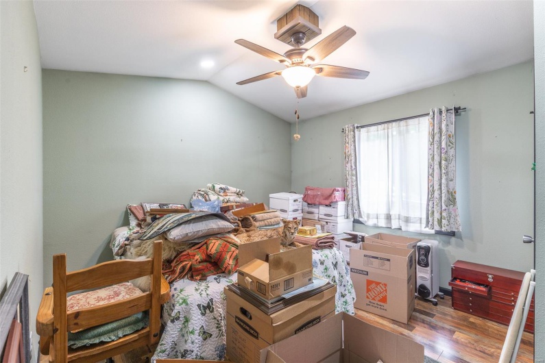 Bedroom featuring wood finished floors, lofted ceiling, and a ceiling fan