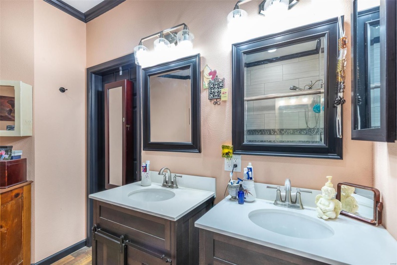 Full bathroom featuring two vanities, ornamental molding, and wood finished floors