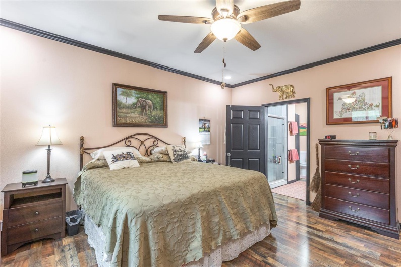 Bedroom featuring ornamental molding, wood finished floors, ensuite bathroom, and ceiling fan