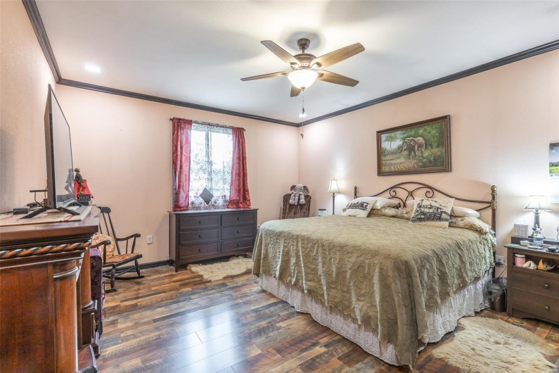 Bedroom featuring crown molding, wood finished floors, baseboards, and ceiling fan