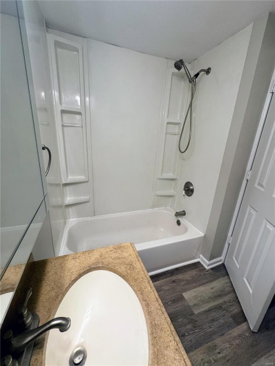 Full bath featuring wood finished floors, shower / washtub combination, a sink, and baseboards
