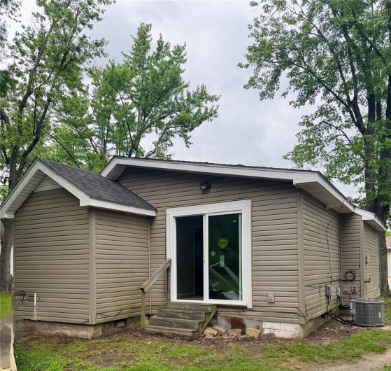 Rear view of property with entry steps, crawl space, and central AC unit