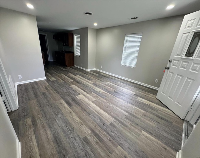 Unfurnished living room with recessed lighting, dark wood-style floors, baseboards, and plenty of natural light