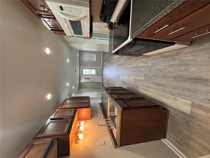 Kitchen with stove, a sink, light wood-style floors, dark countertops, and baseboards
