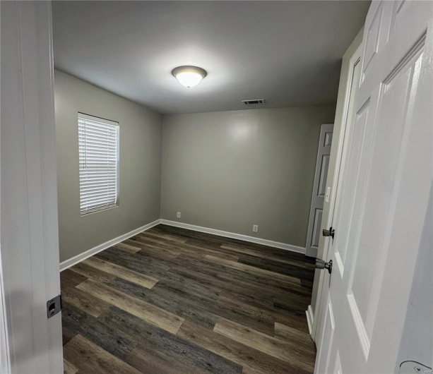 Unfurnished room featuring dark wood-style floors and baseboards