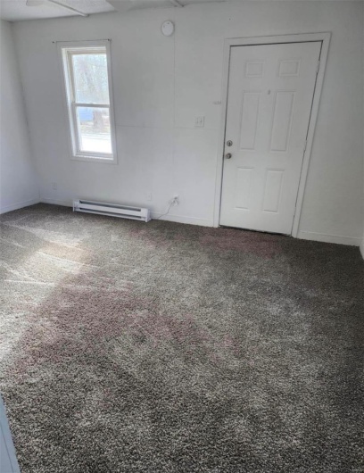 Unfurnished room featuring a baseboard heating unit, carpet floors, baseboards, and a smoke detector