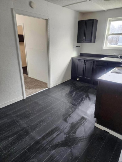 Kitchen with a sink, dark cabinets, and baseboards