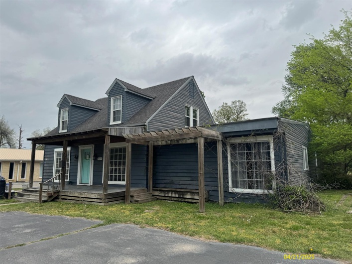 View of front of property with a porch, a shingled roof, and a front yard