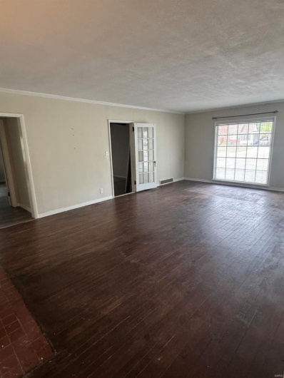 Empty room with dark wood-style floors, plenty of natural light, baseboards, crown molding, and a textured ceiling