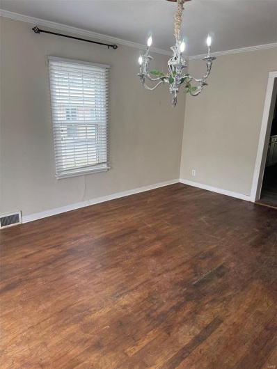 Unfurnished room featuring a chandelier, crown molding, baseboards, and wood finished floors
