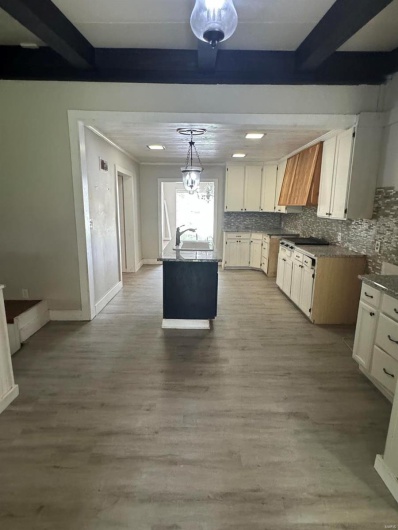 Kitchen with custom exhaust hood, backsplash, beam ceiling, wood finished floors, and pendant lighting