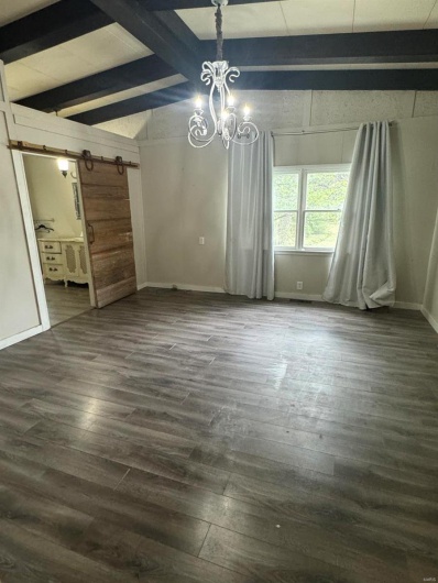 Unfurnished dining area with a chandelier, baseboards, and dark wood-style floors