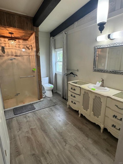 Full bath with a shower stall, beamed ceiling, wood finished floors, toilet, and vanity