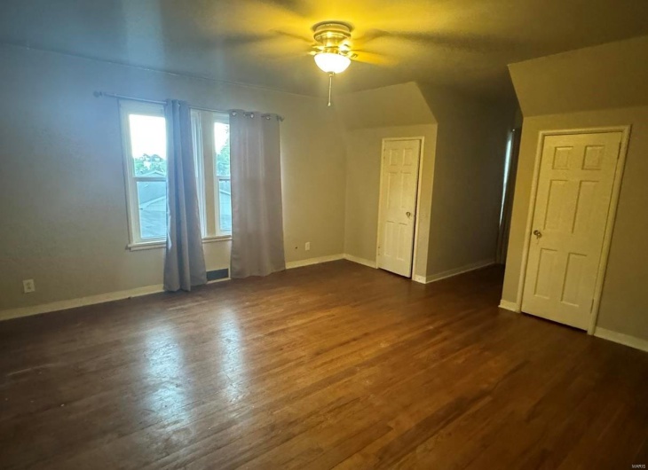 Spare room featuring a ceiling fan, dark wood-style floors, and baseboards