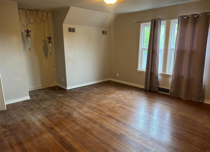 Empty room featuring wood-type flooring, baseboards, and vaulted ceiling
